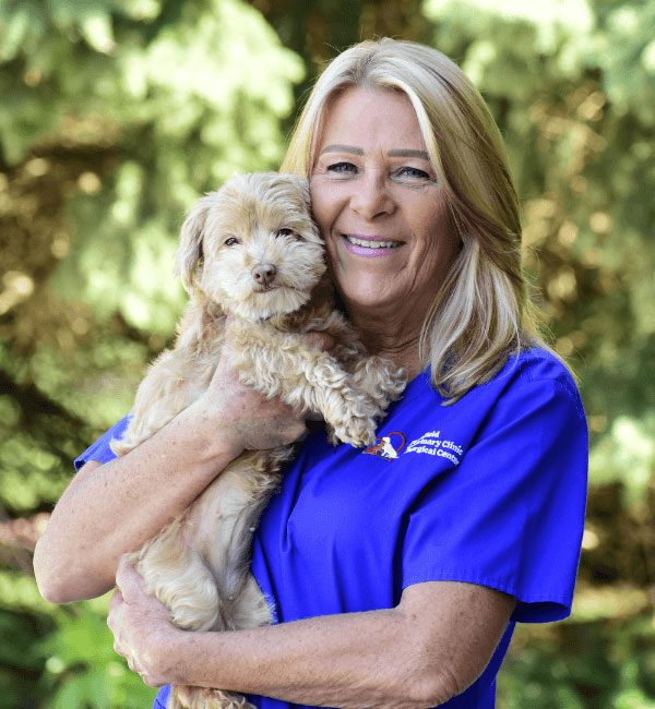 Ami posing for a photo with her poodle under a tree